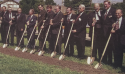 An old photo of local Church leaders in suits holding shovels into the ground.