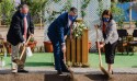 Three people in Sunday best shoveling dirt.