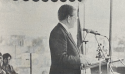 An old photo of Elder Boyd K. Packer speaking at a podium outside.