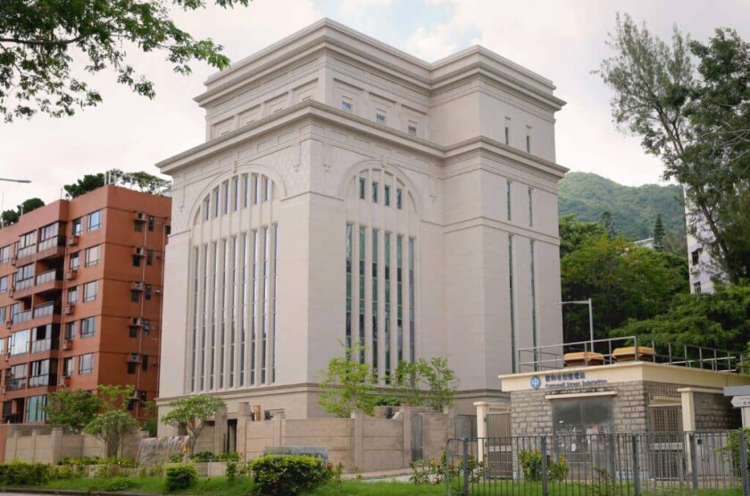 The exterior of the Hong Kong China Temple with three buildings and a mountain in the background.