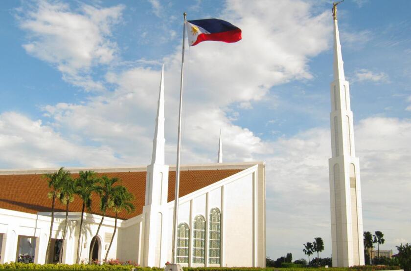 The Manila Philippines Temple, a white building with two large central spires at the front and back with four smaller spires at their sides.