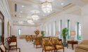 A temple celestial room with white walls, clear chandeliers and armchairs with floral designs.